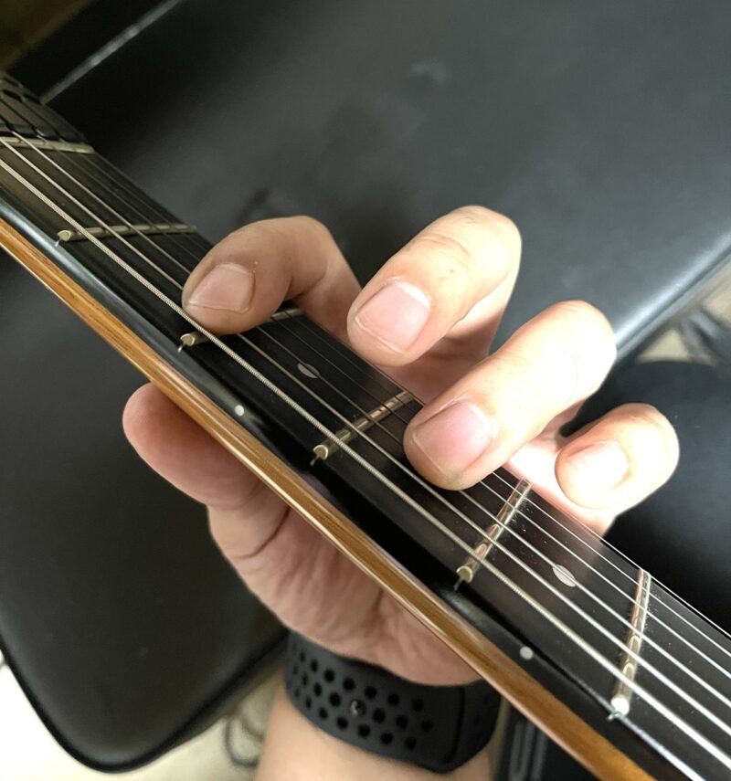 ギターの弦を押さえる左手のクローズアップ